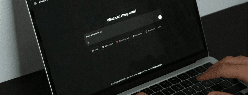 A person sitting in front of a laptop with the screen open to an AI chatbot interface in dark mode. The user is typing on the keyboard.